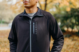 Man wearing a black Aheata zip up jacket with a vertical chest pocket