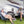 AlphaCool portable fan on a table between two people sitting in camping chairs outside a recreational vehicle
