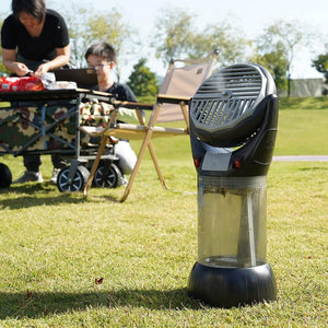 Portable misting fan on a grassy field with people camping in the background