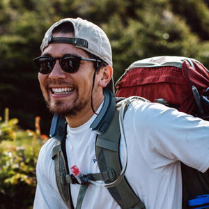 Hiker wearing an AlphaCool neck fan while carrying a backpack