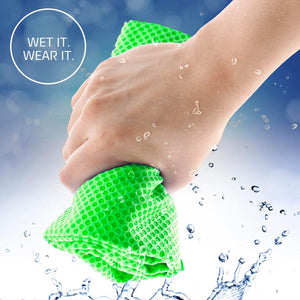 Hand holding a wet green cooling towel with water droplets