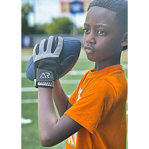 Boy wearing Arctic Reaction football gloves holding a football on a field