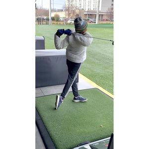 Person wearing Arctic Reaction white jacket swinging a golf club on a driving range