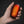 Hand holding a black oval device with an illuminated orange hexagonal pattern