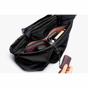 Bellroy black tote bag interior with organized pockets and a hand holding a key cover attached to a lanyard