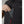 Hand placing a battery pack into the zippered chest pocket of a black Lenz vest