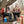 Couple sitting in camping chairs by a fire pit with Coleman cooler and mugs