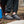 Person wearing grey slip on outdoor slippers with black toggle closure