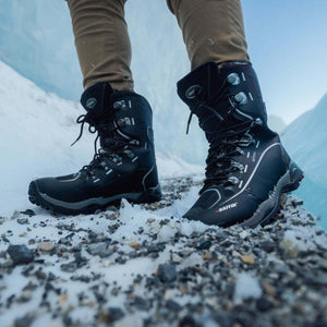Person wearing black Baffin softshell winter boots standing on snowy rocky ground