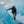 Person wearing a black parka and tan pants standing between blue glacier walls