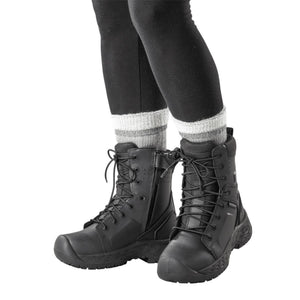 Person wearing black tactical boots with side zippers and grey striped socks