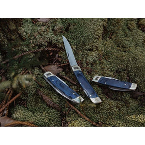 Three Barebones pocket knives with blue wood handles resting on mossy ground