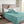 Person reading a book in bed covered by a teal Beautyrest plush blanket
