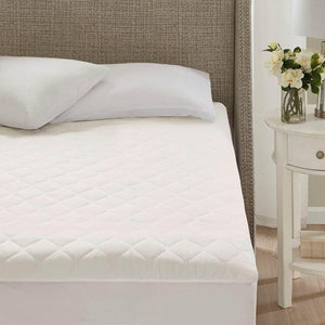 Beautyrest white quilted mattress pad on a bed with pillows and headboard