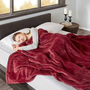 Person sleeping under a red Beautyrest heated blanket on a bed