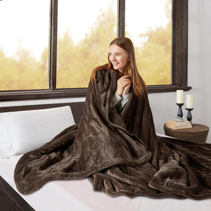 Person wrapped in a brown Beautyrest heated throw blanket on a bed