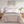 Beige textured blanket draped over a bed with white pillows and wooden nightstands