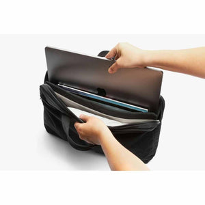 Hands sliding a laptop into a black Bellroy laptop sleeve