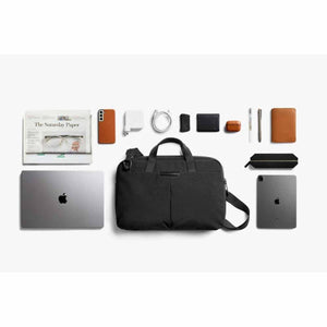 Bellroy black briefcase surrounded by laptop tablet phone charger pens and personal accessories