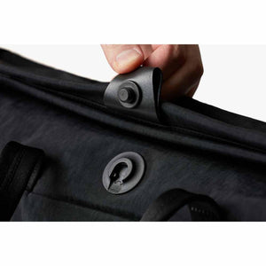 Hand fastening the magnetic snap closure on a black Bellroy bag