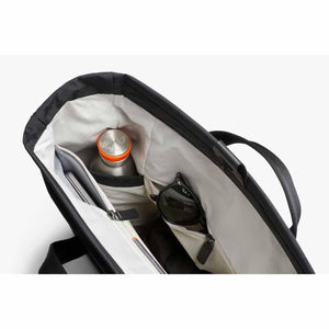 Interior view of a black Bellroy tote bag showing a water bottle and sunglasses in organized pockets