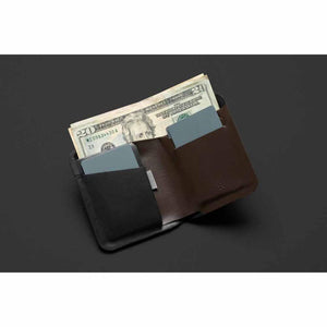 Bellroy brown leather wallet containing two grey cards and US currency