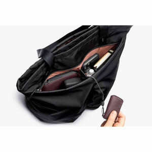 Bellroy black tote bag interior with organized pockets and a hand holding a key cover attached to a lanyard