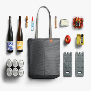 Bellroy tote bag surrounded by picnic items including wine bottles, canned drinks, fruit, cheese, and ice packs