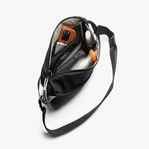 Open Bellroy sling bag containing a phone, water bottle, and small accessories