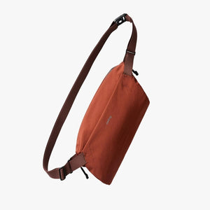 Rust colored Bellroy sling bag with adjustable brown strap