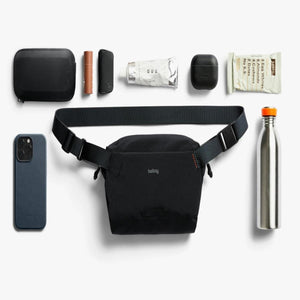 Bellroy sling bag surrounded by everyday carry items including a smartphone, water bottle, and small accessories