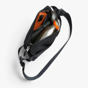Open Bellroy sling bag containing a smartphone and a metal water bottle
