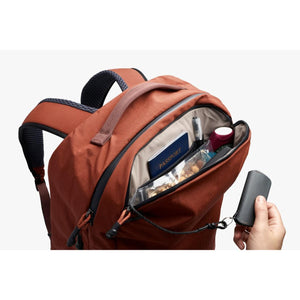 Bellroy backpack with open front pocket containing a passport and snacks with a key clip attached