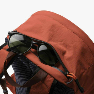 Sunglasses resting on the top zipper pocket of a Bellroy backpack