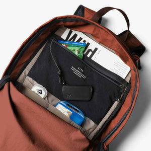 Open Bellroy backpack interior showing organized pockets with accessories and a magazine