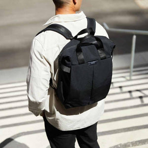 Person wearing a black Bellroy backpack with top carry handles