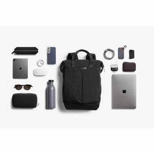 Bellroy black backpack surrounded by organized tech accessories and personal items on a white background