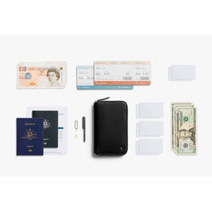 Bellroy travel wallet with passport, boarding passes, currency, cards, and pen laid out on white background