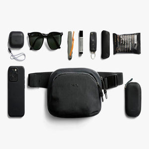 Bellroy sling bag surrounded by everyday carry items including phone case, sunglasses, keys, and snacks