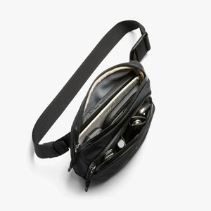 Open Bellroy sling bag with organized compartments containing a phone and keys