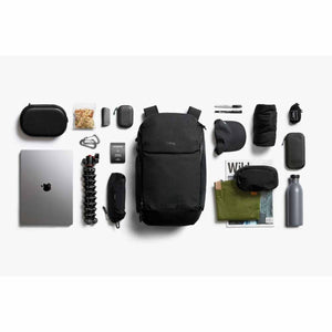 Bellroy backpack surrounded by organized travel accessories and electronics on a white background