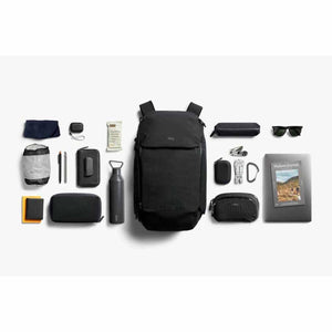 Bellroy backpack surrounded by organized travel accessories and personal items on a white background