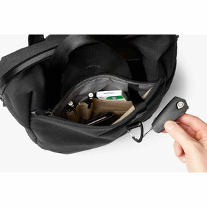 Hand holding a Bellroy key cover near the open interior pocket of a black Bellroy bag