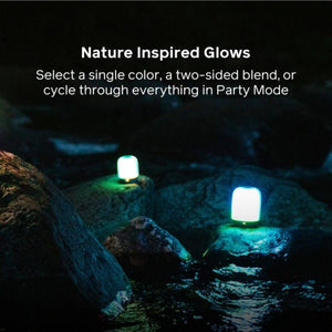 Two BioLite lanterns glowing on rocks by a stream at night