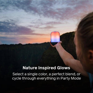 Person holding a glowing BioLite lantern against a sunset landscape
