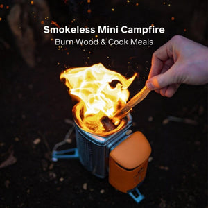 Hand placing wood into a portable smokeless mini campfire stove