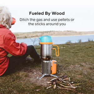 BioLite wood burning camp stove with kettle on grass near a lake