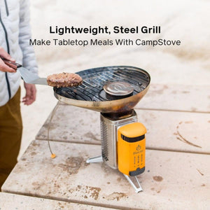 BioLite CampStove with steel grill attachment cooking a burger patty on a tabletop