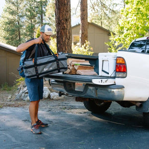 Person loading a BioLite gear bag into the back of a pickup truck