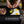 Hands cracking an egg onto a BioLite pre-seasoned cast iron griddle with bacon and eggs cooking